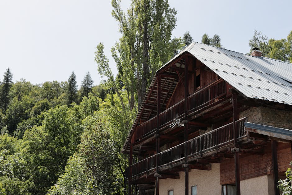 Rustic chalet with wooden balconies nestled in a lush forest in Puy-Saint-Vincent, France.