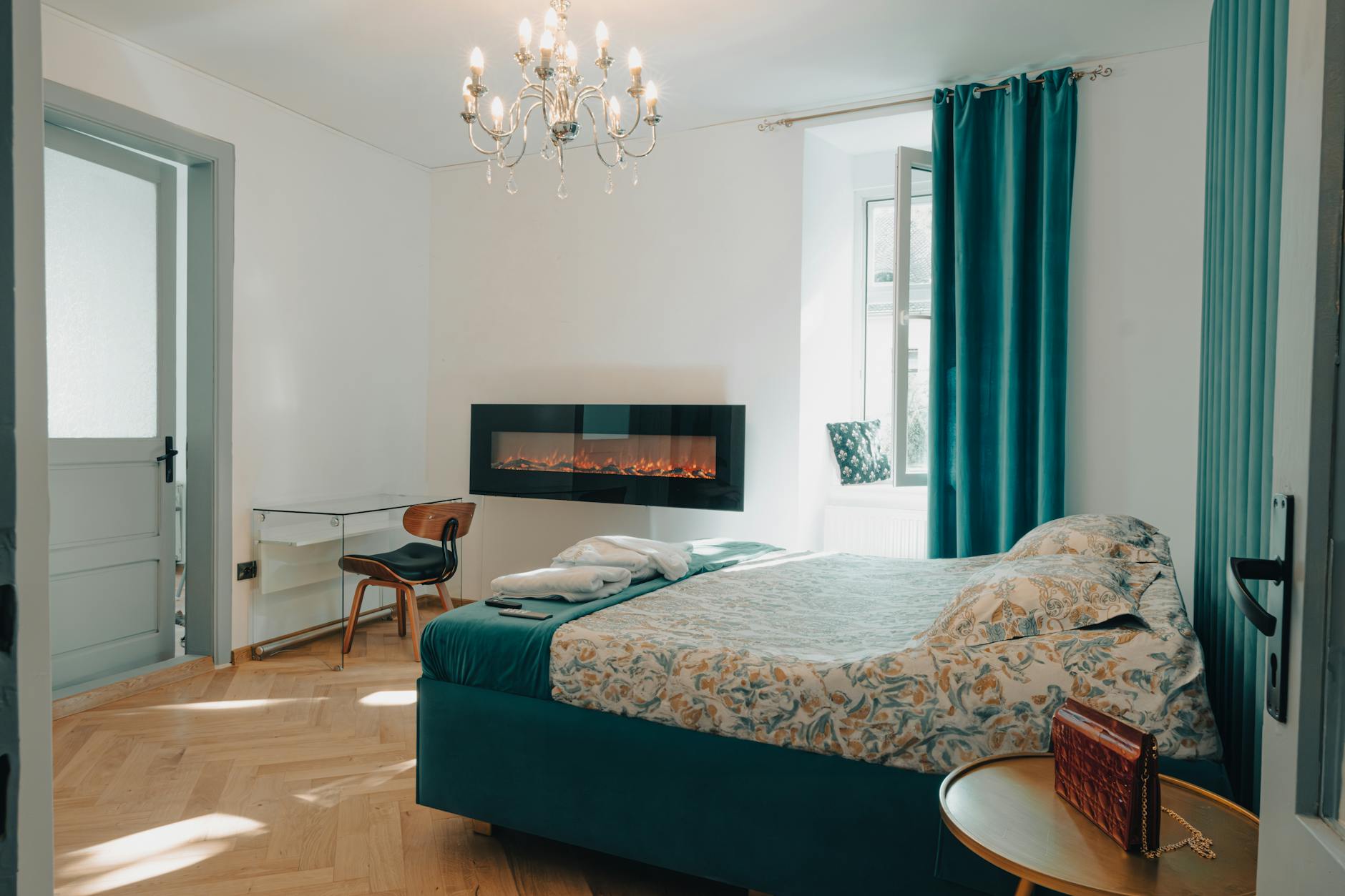 Elegantly decorated bedroom featuring an electric fireplace and teal accents for a cozy ambiance.